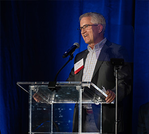 Man at a podium at a awards ceremony.